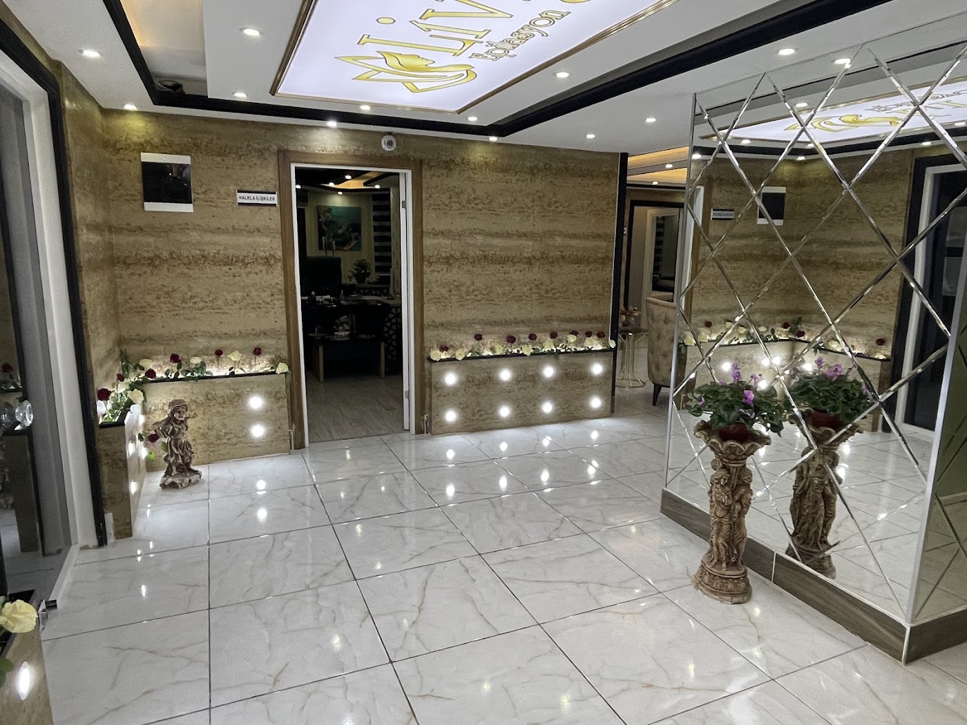Livmed güzellik merkezi giriş holü — traverten duvarlar ve altın logo